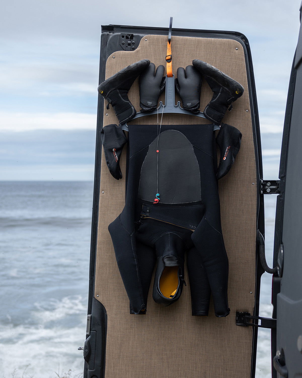 C-Monsta grey wetsuit hanger in use – wetsuit and surf gloves hanging to dry, lifestyle shot